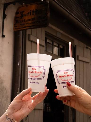 Two Purple Drank cups toasting outside Lafitte's Blacksmith Shop on Bourbon Street